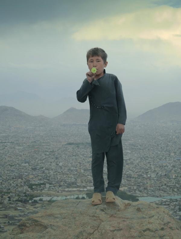 Un jeune garçon jouant du kazoo sur le haut plateau près de Kaboul