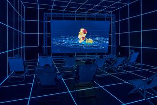 People seated in a dark room of a glowing blue grid, watching a surreal video.