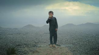 Un jeune garçon jouant du kazoo sur le haut plateau près de Kaboul