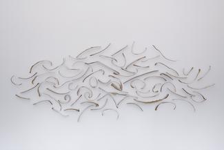 Pieces of tear strips from cardboard packaging are arranged to form the shape of a cloud.