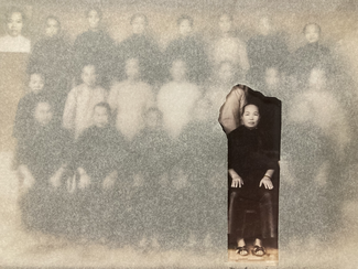 C'est une photographie ancienne en noir et blanc montrant un groupe de personnes posant ensemble. L'image est partiellement altérée, rendant certaines personnes floues ou à peine visibles. Sur la droite, il y a une partie qui se détache où une femme est clairement visible, assise sur une chaise, regardant vers l'avant. Sa tenue est traditionnelle, et elle se distingue du reste de l'image à cause de cette démarcation nette.