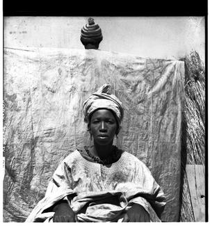 portrait de femme en boubou, devant une personne de dos tenant un pagne tendu