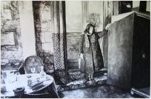Debout manteau noir, porte-fenêtre, table à gauche - 1984